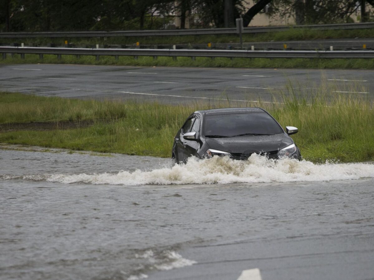 Vehículo cruzando una carretera inundada en la PR-2 en Aguadilla tras lluvias intensas, evidenciando el impacto de la falta de planificación ambiental y manejo adecuado del drenaje en zonas kársticas.